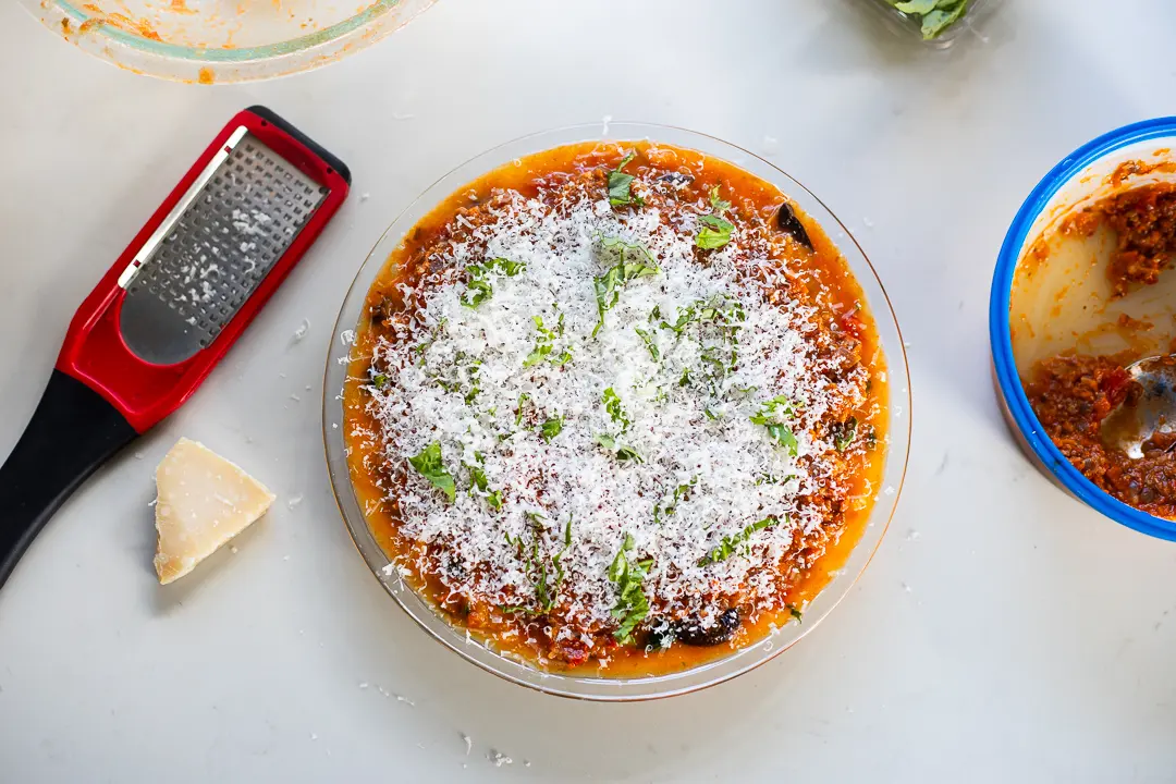 Spaghetti squash pizza pie with grated Parmesan, ready to bake