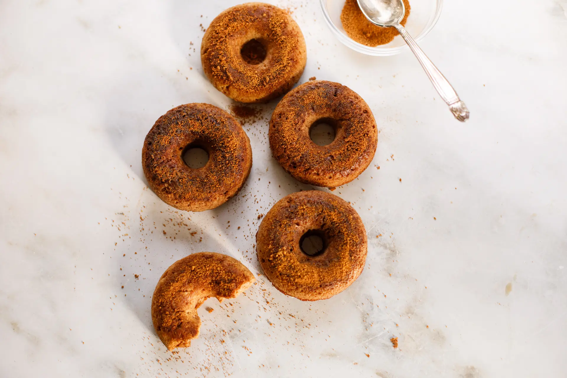 Apple Cider Donuts being topped with cinnamon coconut sugar mixture
