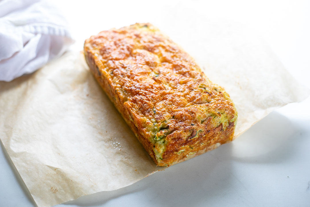 full baked cheddar zucchini bread on top of parchment paper on counter