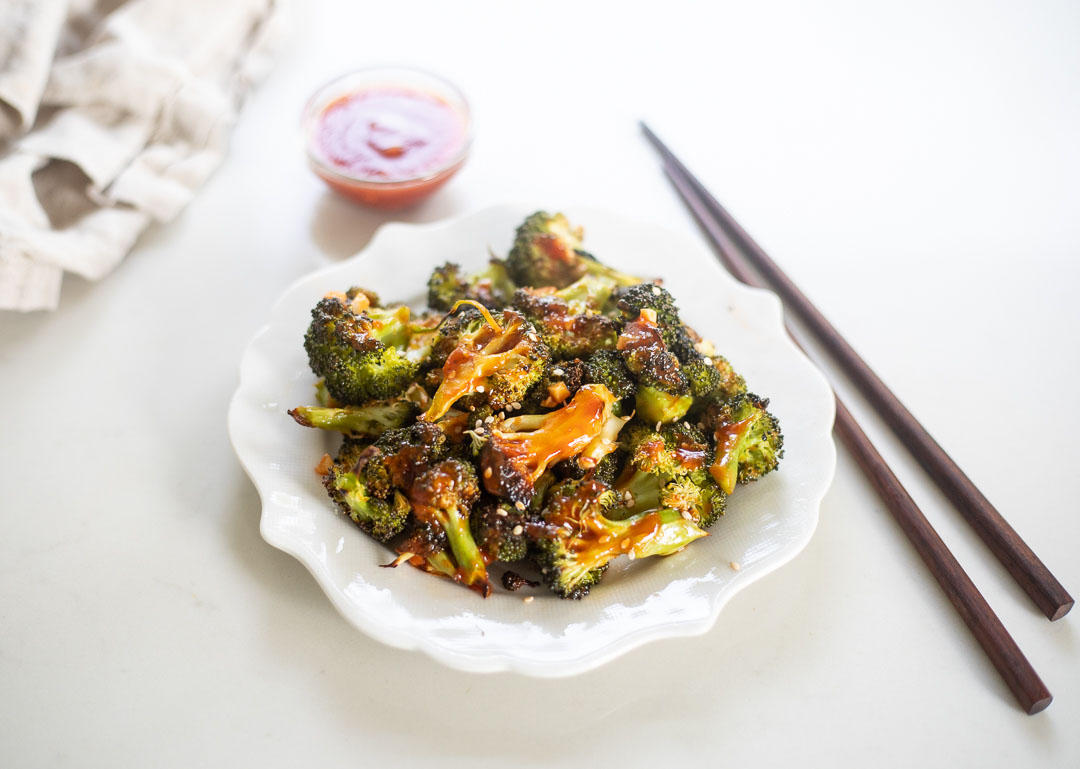 Orange sesame broccoli on plate with sauce and chopsticks