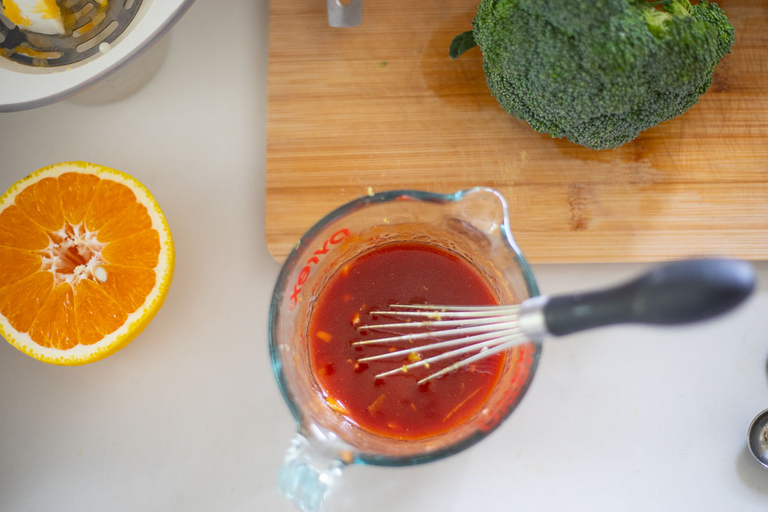 Orange sauce in bowl with whisk